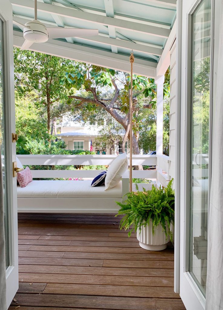 View Of White Hanging Daybed Swing Under Covered Porch Through Open French Doors