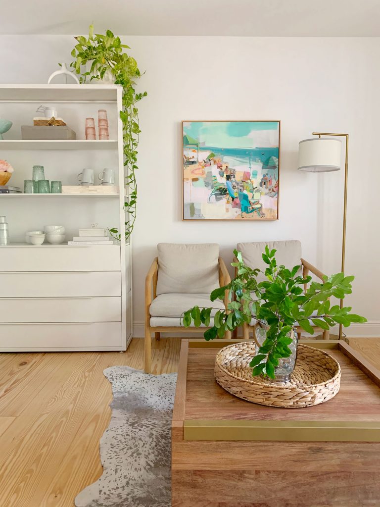 Side view of sitting area with plants on coffee table and hanging from kitchen shelf