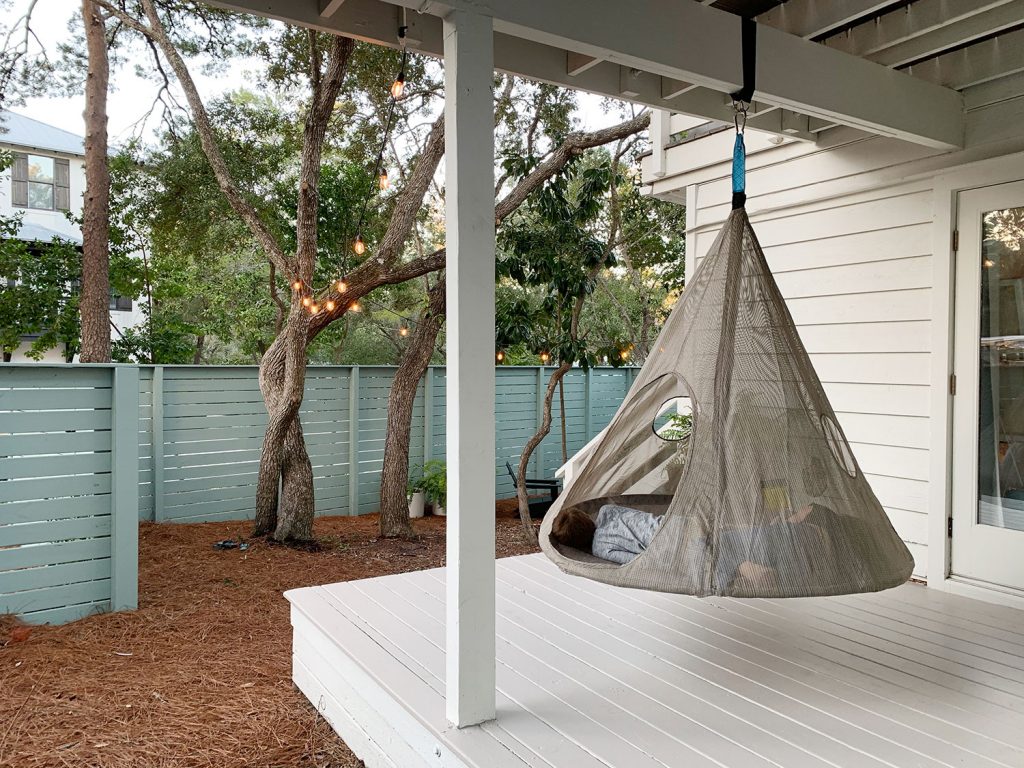 Two kids laying in hanging tent on covered porch