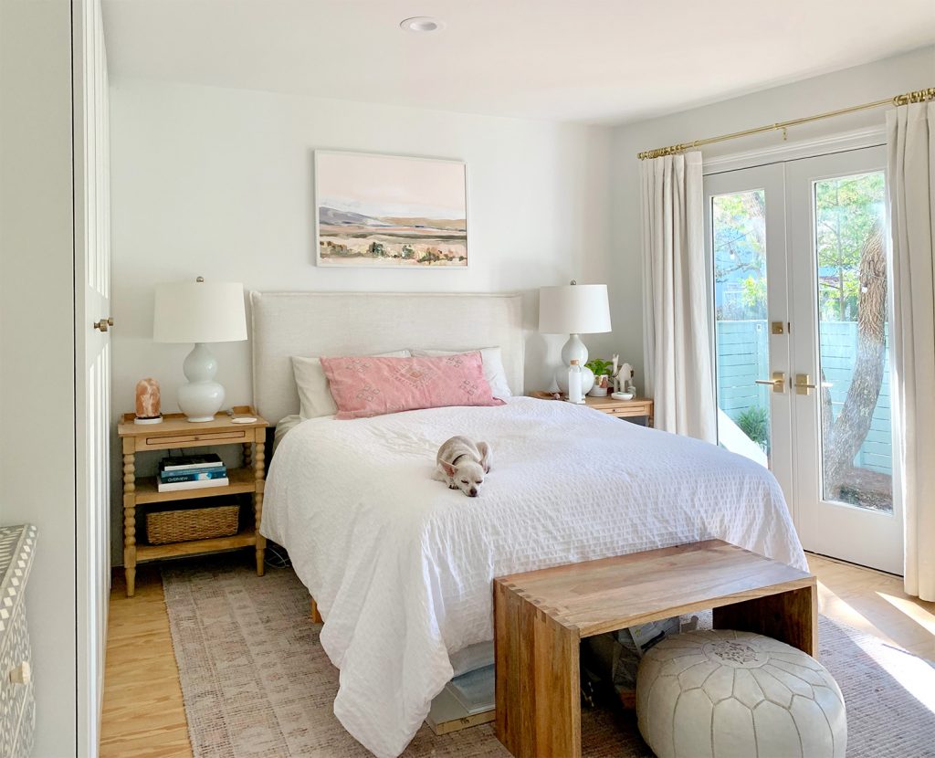 Bedroom with pink rug with french doors next to white bed