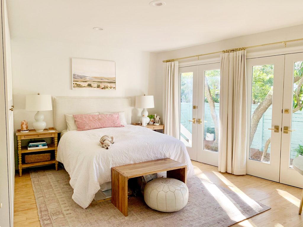 Bedroom with pink rug with french doors next to white bed