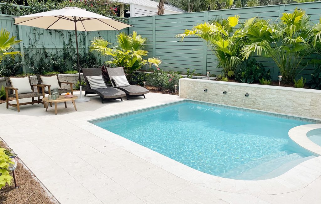 Seating area next to pool with tropical greenery on retaining wall