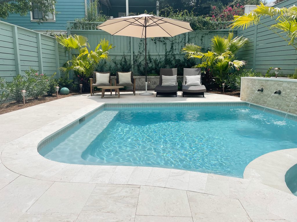 Small Backyard Pool With Curved Edges and Fountains With Patio Furniture In Background