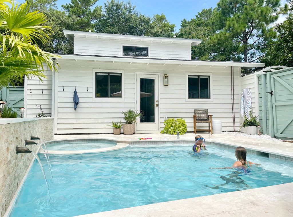 Two kids playing in small freeform pool with scupper fountains on wall