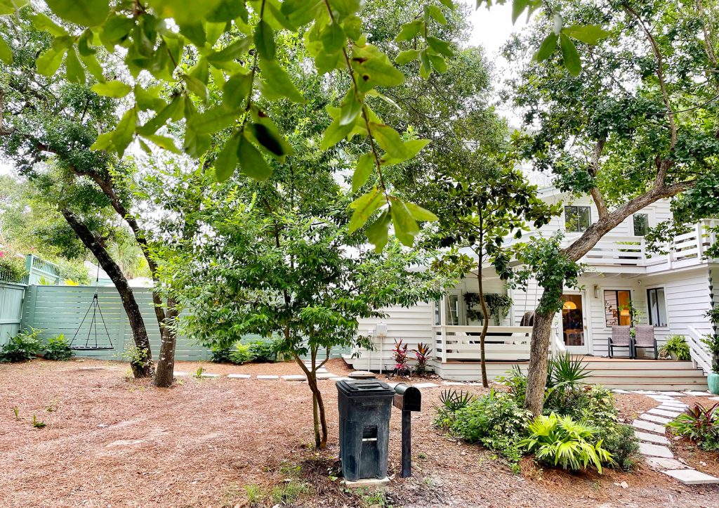 After photo of house from street with green fence in the background