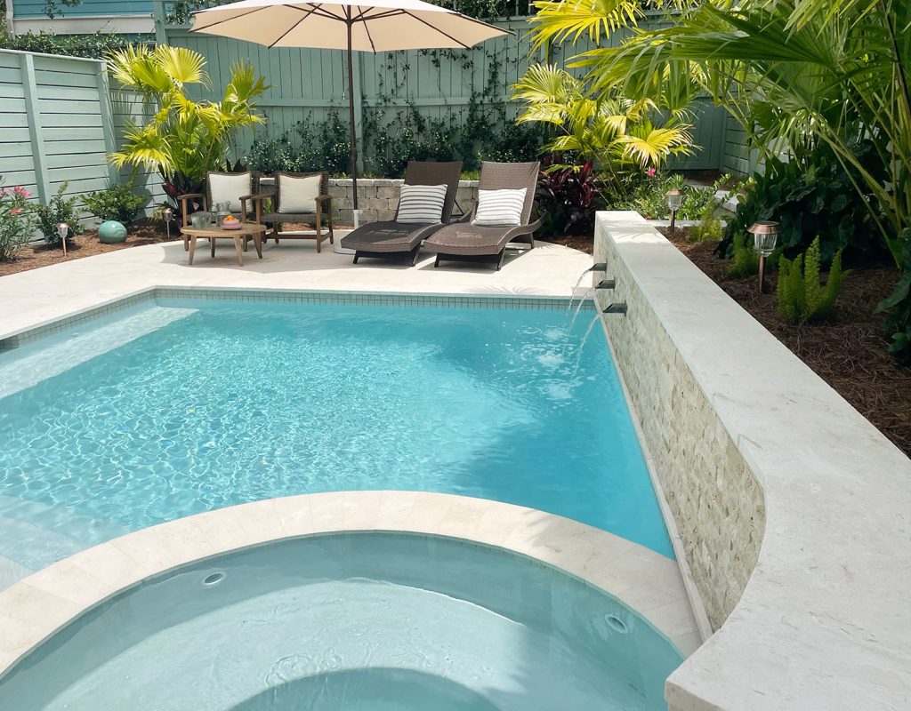 View of curved tile accent retaining wall covered in stone with fountains into pool