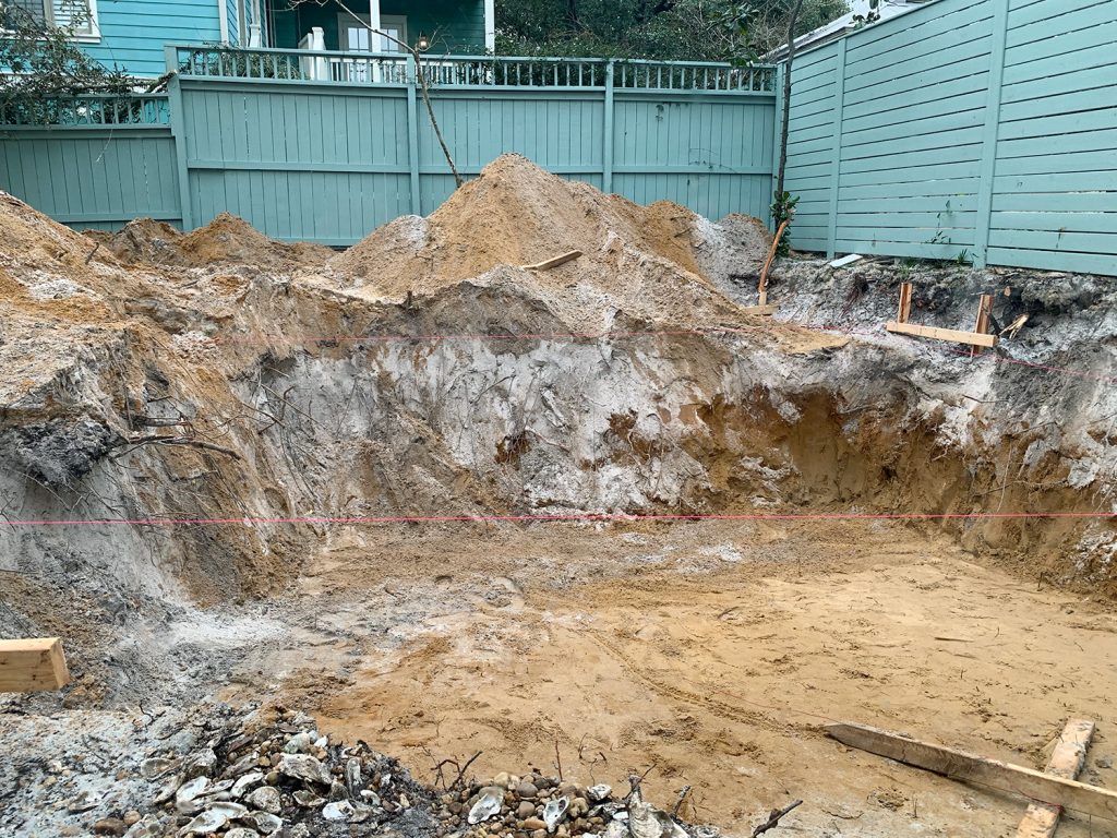 Large dirt hole dug in backyard where pool will be constructed