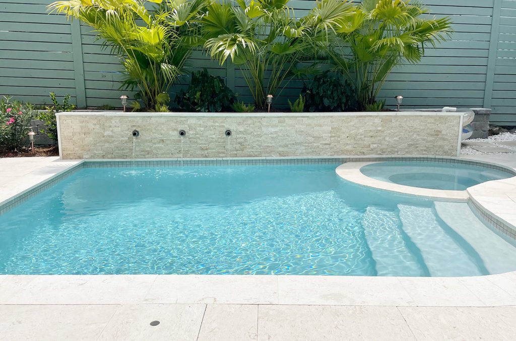 Pequena piscina de forma livre com muro de contenção de ladrilhos de pedra acentuada, ladeada por muro de contenção de blocos cinza