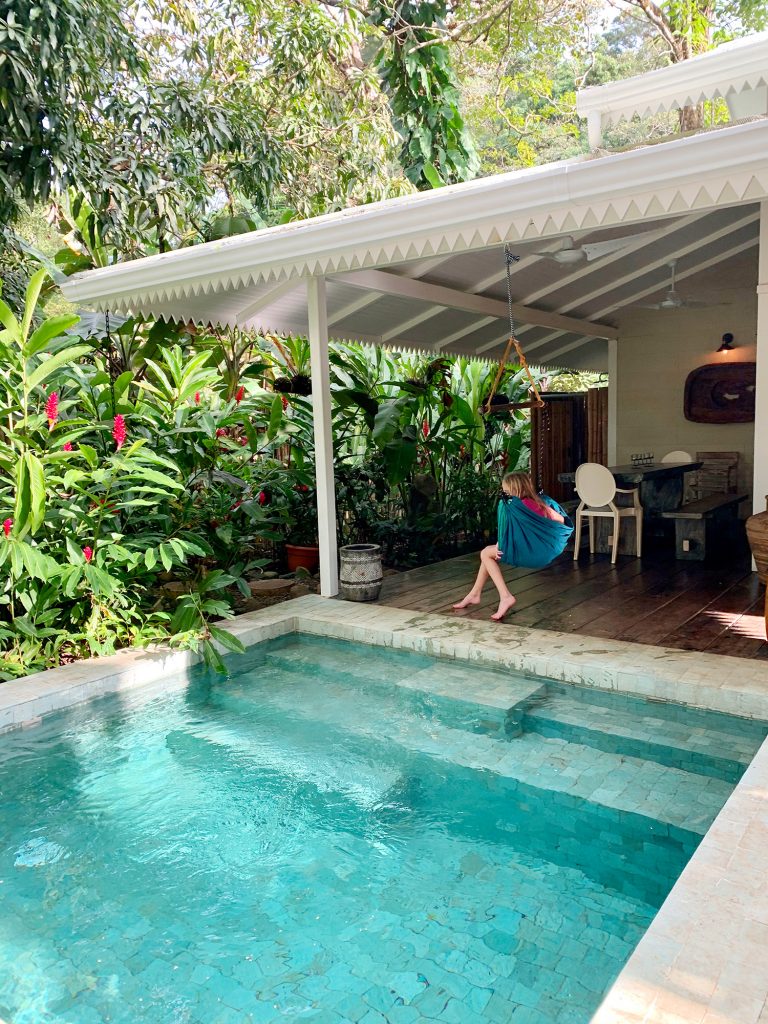 Foto de inspiração de uma pequena piscina tropical ao lado de uma casa branca e uma criança no balanço