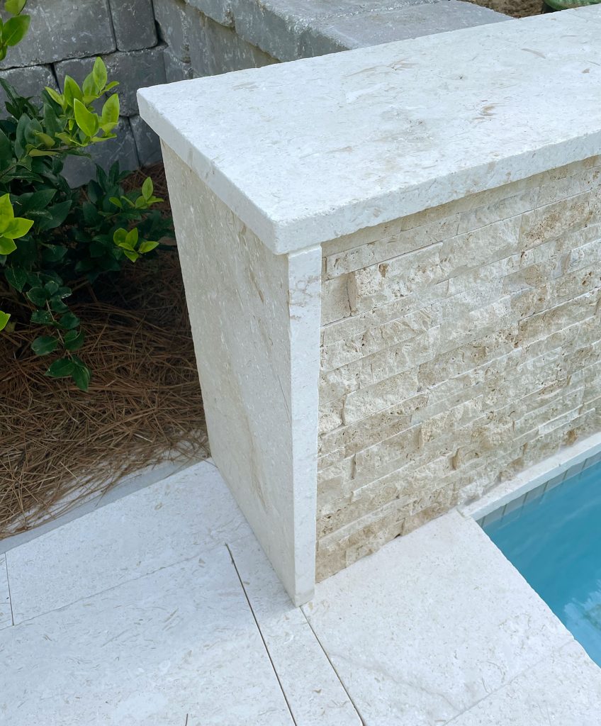 Detail photo of shellstone travertine patio tile used along the side and top of tile accent wall