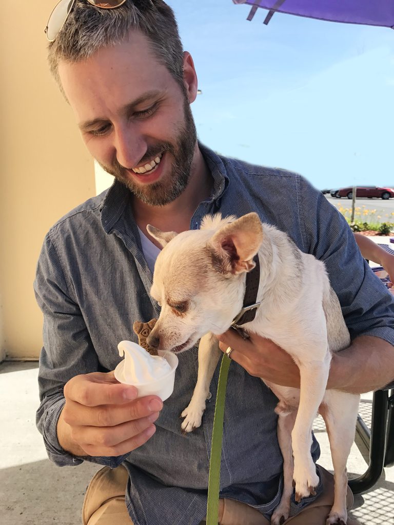 Burger licking ice cream pup cup in John's arms