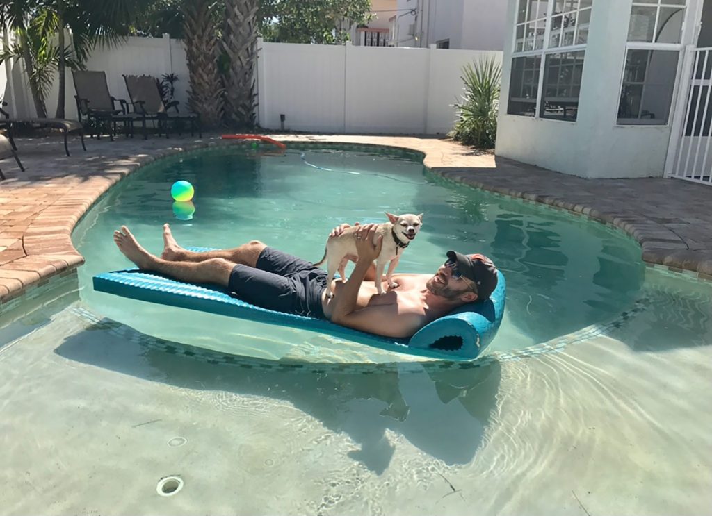 Burger making smiley face while on John's stomach in pool float