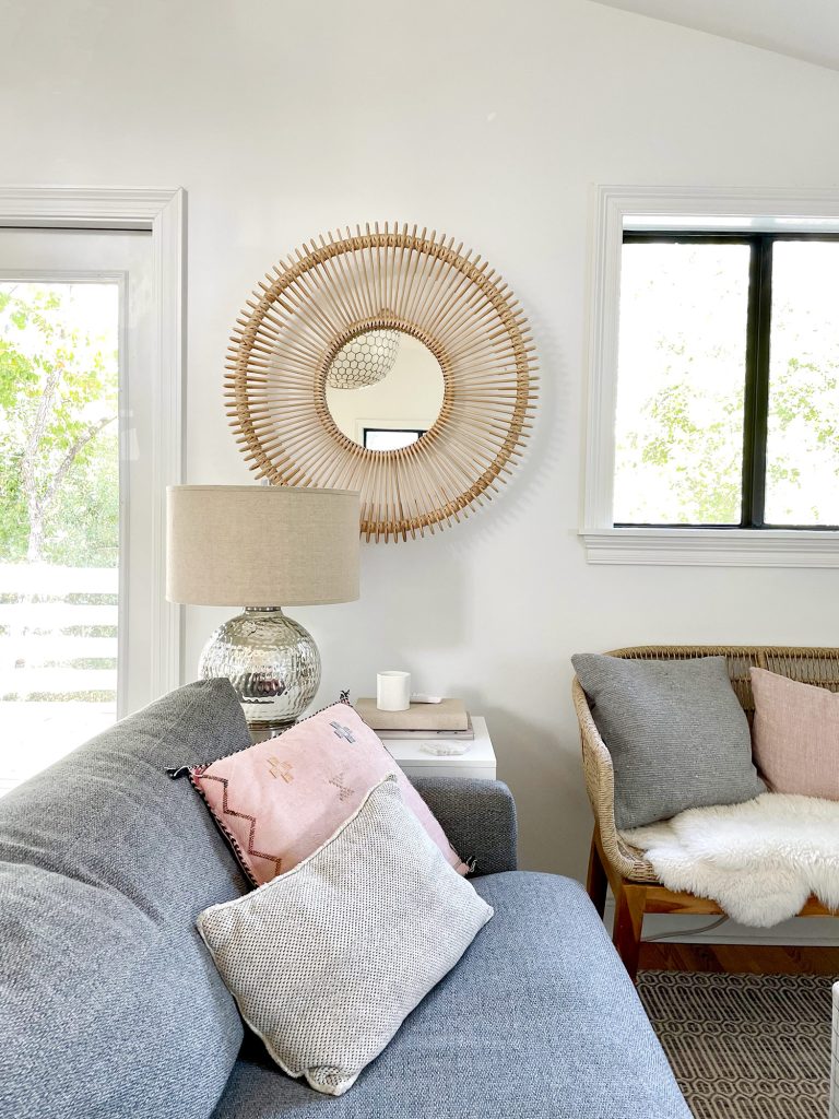 Round Woven Mirror Behind Side Table Next to Family Room Couch