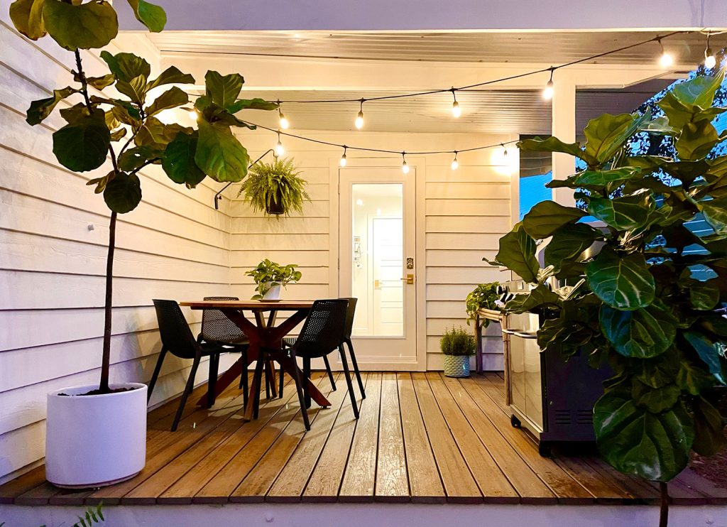 Viewing of dining table on covered kitchen porch under the glow of string lights