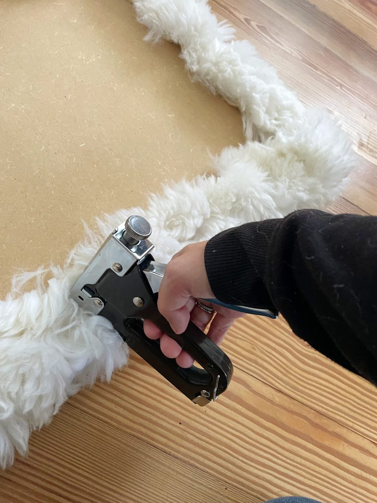 Sherry stapling old sheepskin rug around loveseat base to upholster