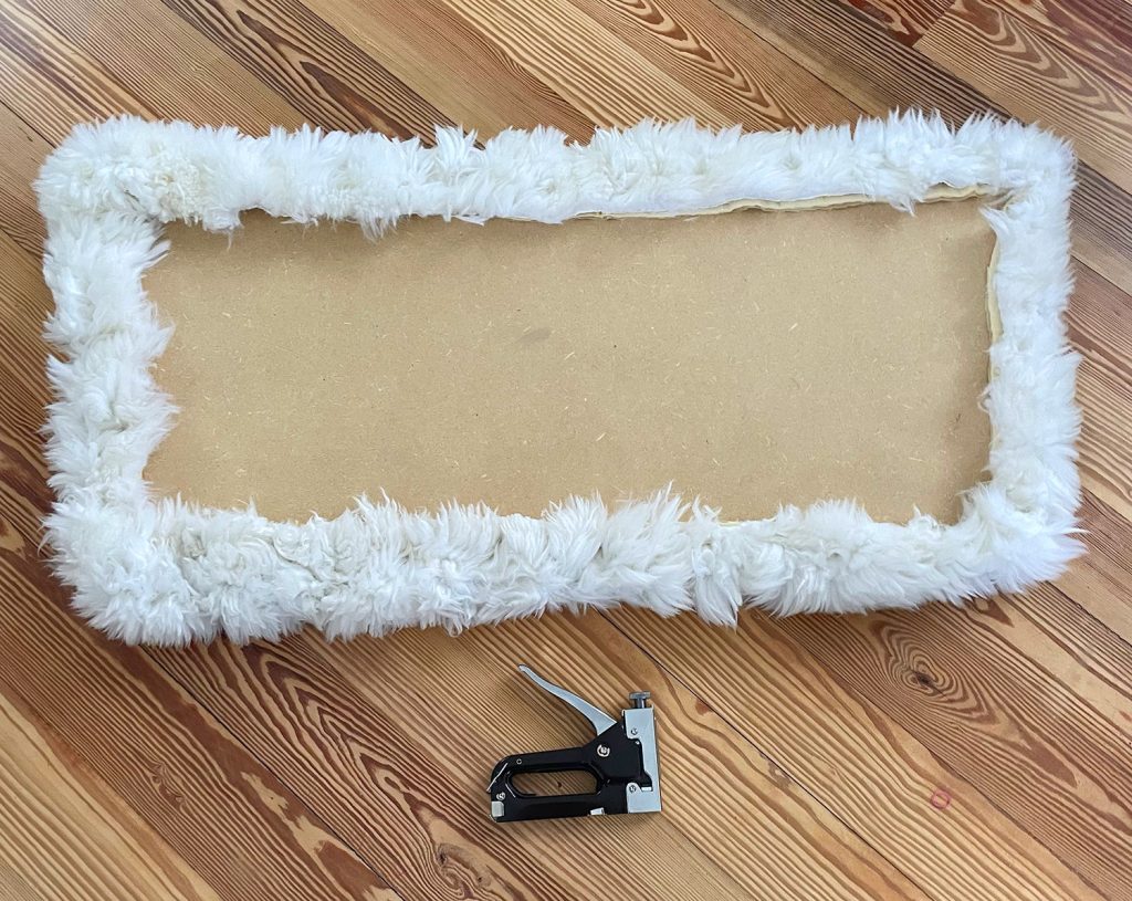 Backside of loveseat seat upholstered with sheepskin rug