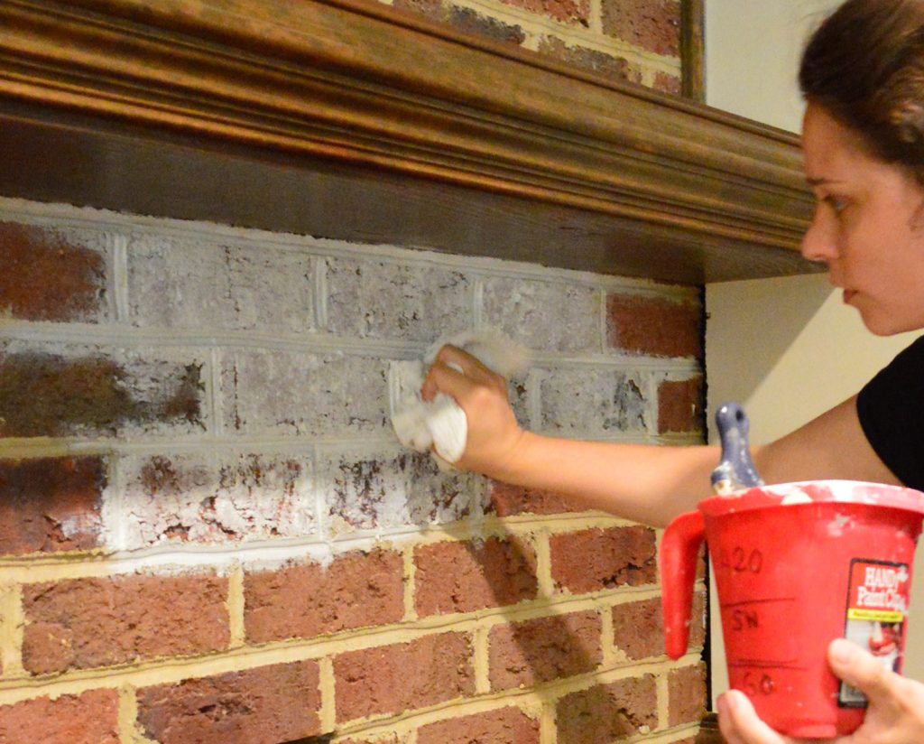 Sherry dabbing watered down white paint on brick wall