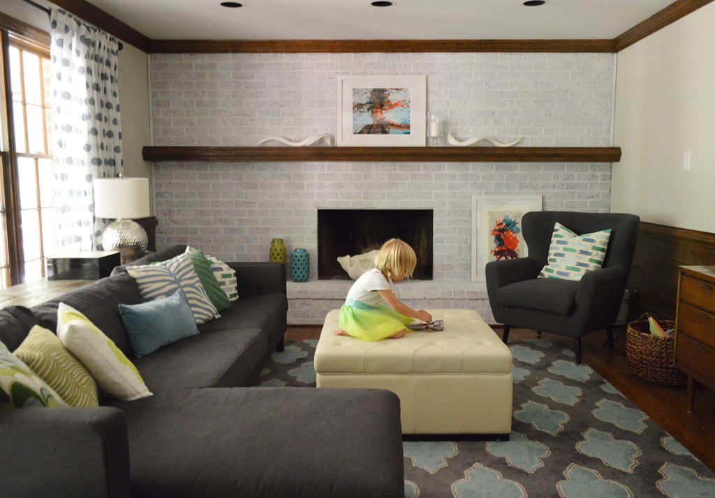 living room with navy blue furniture and a whitewash brick fireplace wall