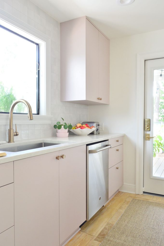 Angled View Of Painted Mauve Pink Kitchen Cabinets With Gray Backsplash