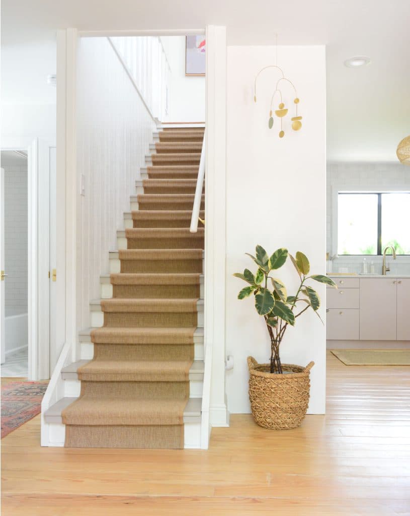 Entry Stairway With Jute Runner And Beachy Kitchen In Background