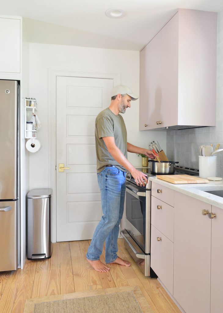 John Standing At Stove Cooking In Mauve Painted Ikea Kitchen