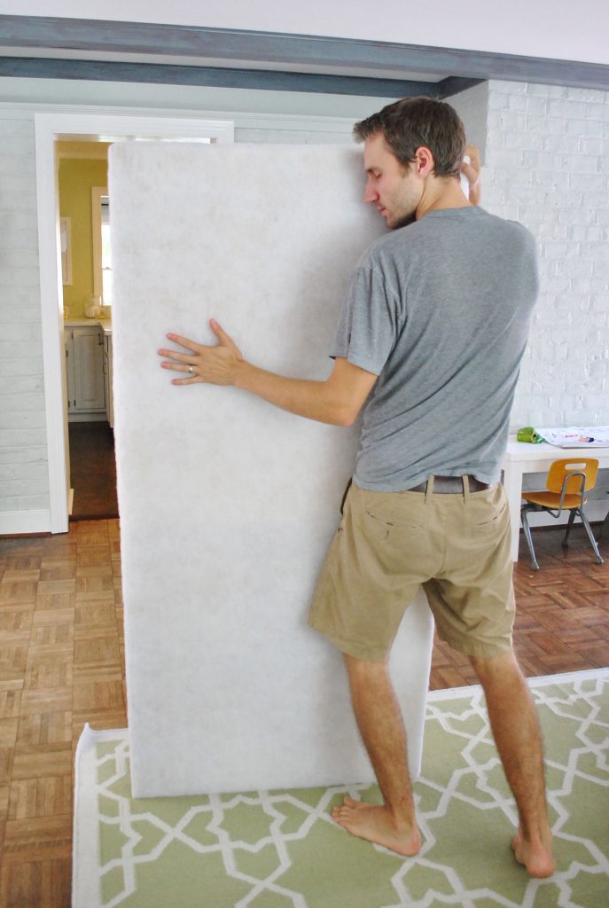 John holding finished headboard covered with batting