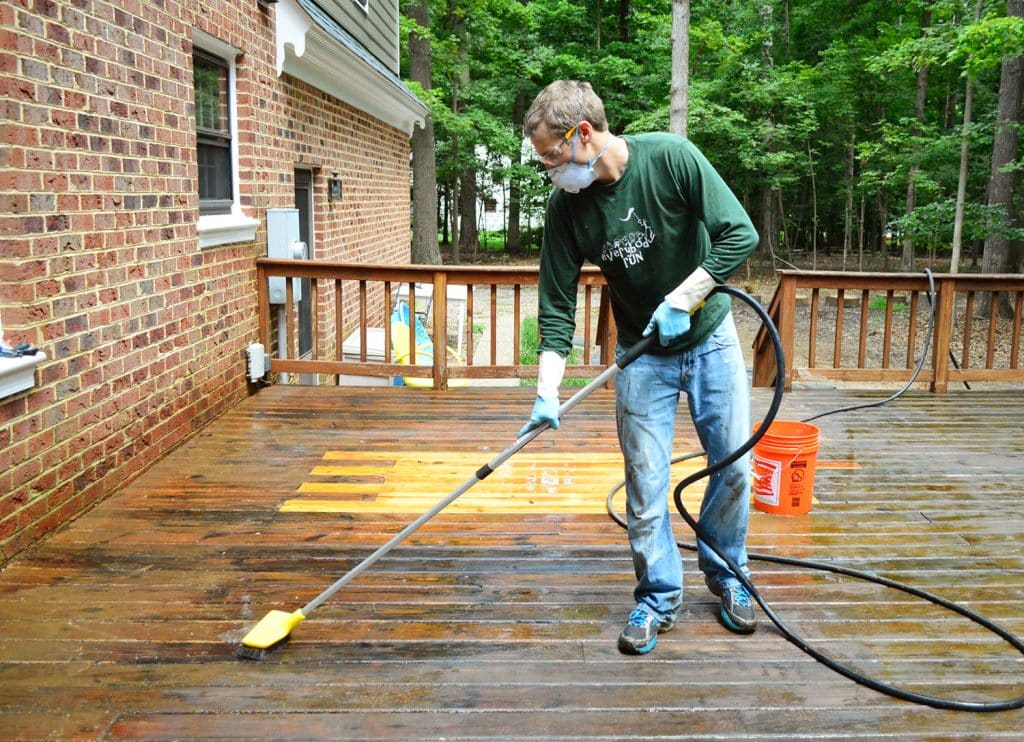 John scrubbing deck with brush attached to hose