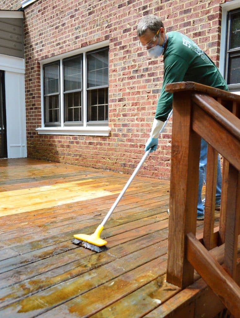 John Scrubbing wood deck to remove old finish with stiff brush