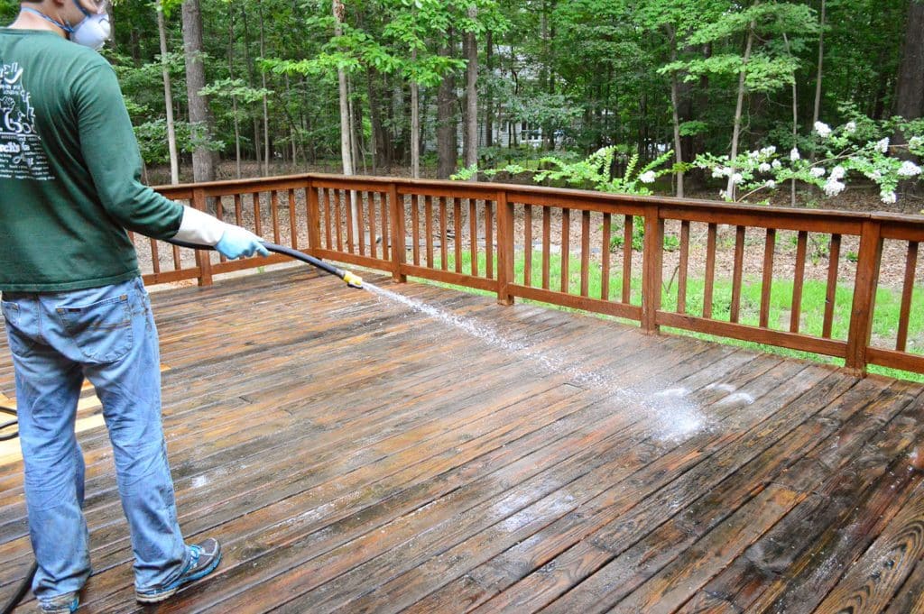 John rinsing deck cleaner off with garden hose