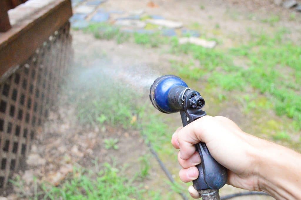 Hose spraying grass and plants near deck