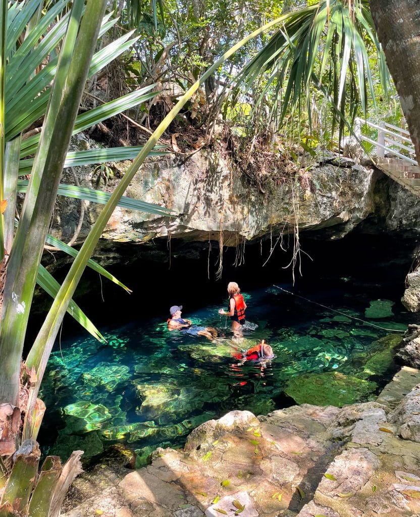 Family Swimming Under Cave At Cenote Cristalino in Akumal Mexico