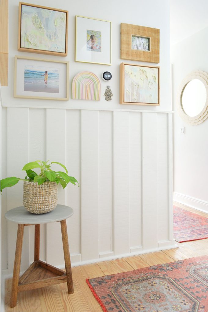 White hallway with wainscoting and picture frame collage and turkish runner rugs