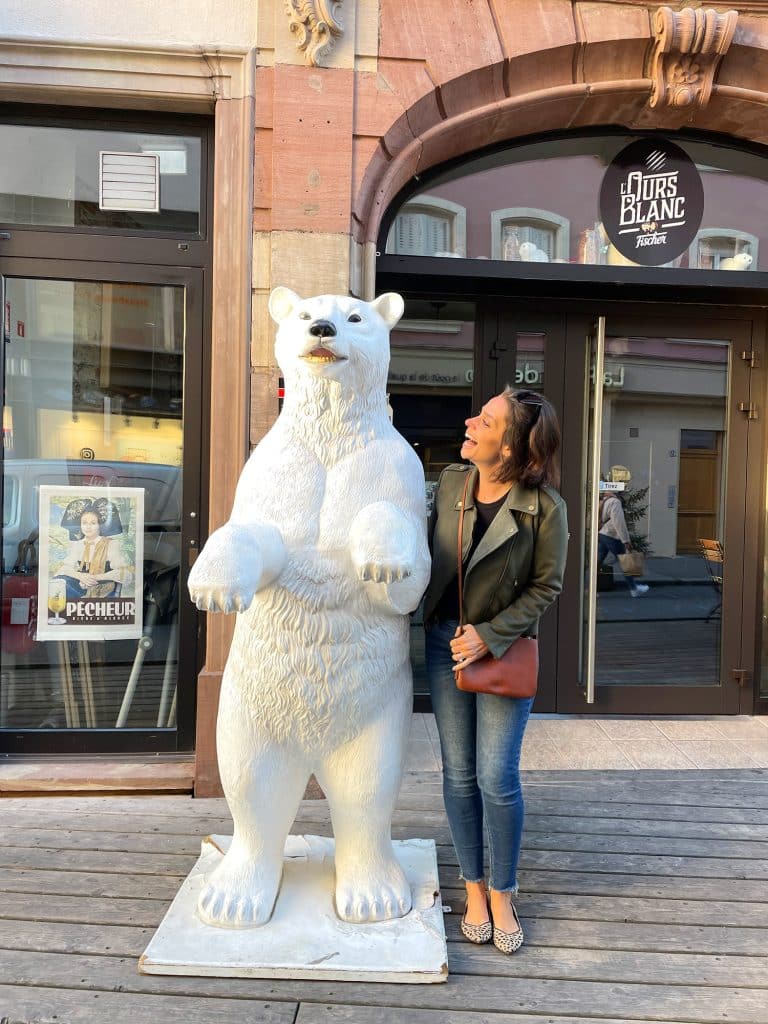 Sherry posing with a polar bear statue with green jacket and black tank and jeans