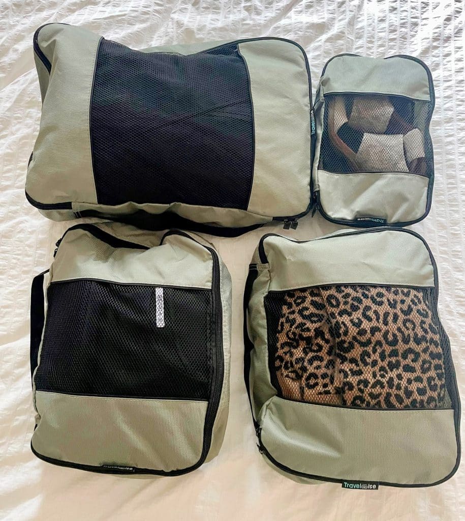 Gray zippered packing cubes on bed with minimal outfits for international trip to France