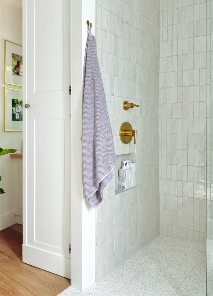 Shower Wall With White Zellige Tile And Brass Hardware And Lavender Towel