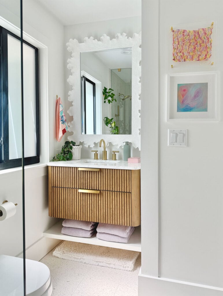 White Bathroom With Floating Wood Vanity and Colorful Accessories