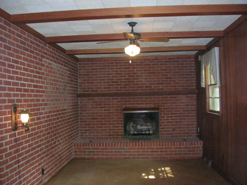 Dated Den With Dark Wood Beams Brick And Wood Paneling