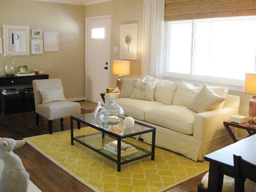 neutral living room with white sofa graphic yellow rug and glass and iron coffee table